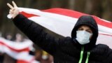 A man carrying a former white-red-white flag of Belarus gestures the V-sign in Minsk, on December 13, 2020. 